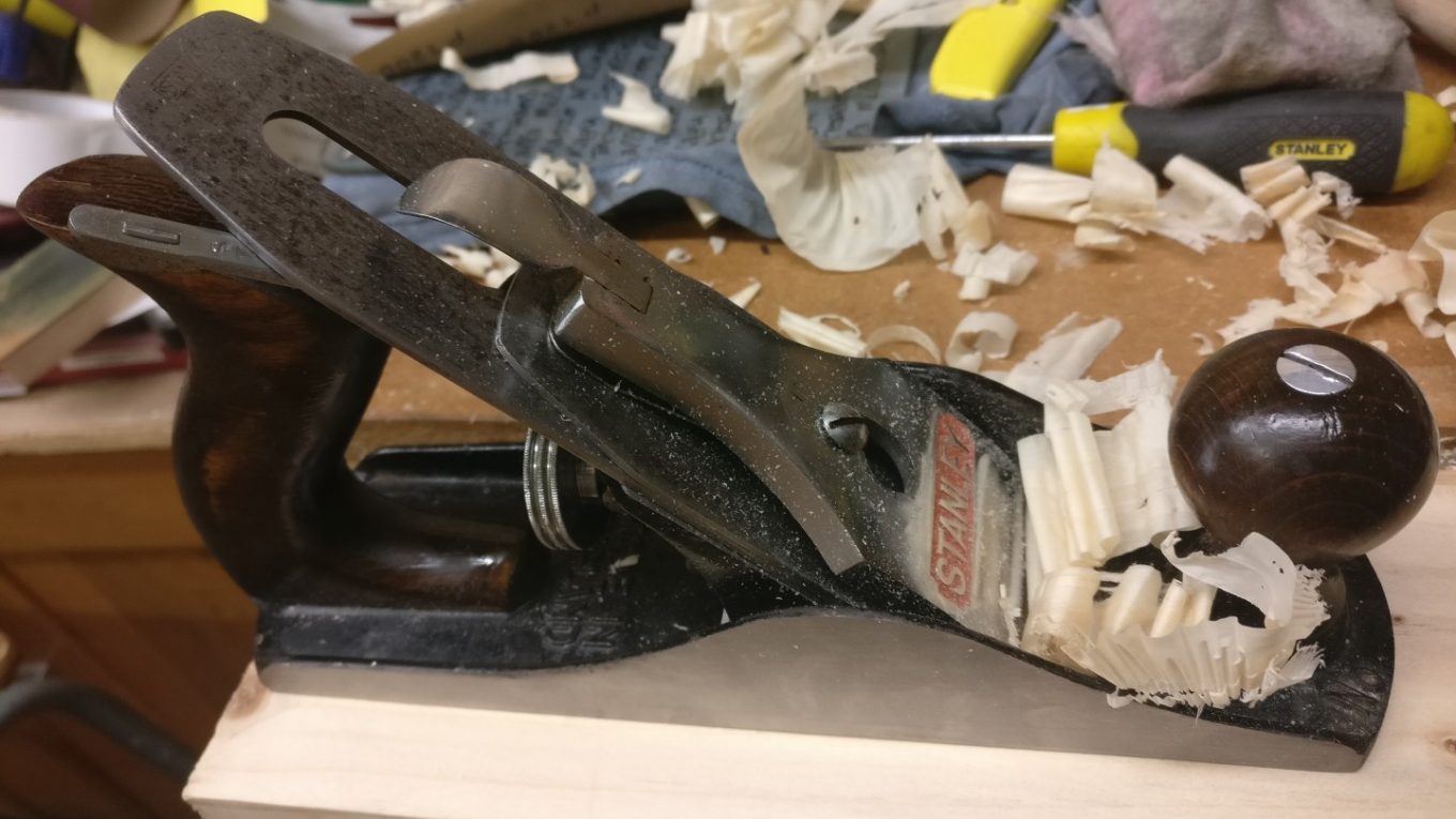 A restored Stanley No. 4 plane cutting a shaving