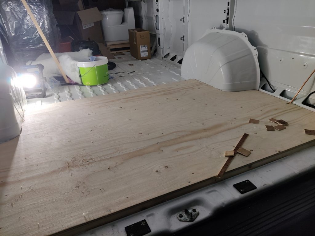 The inside of the van with part of the floor boarded with plywood